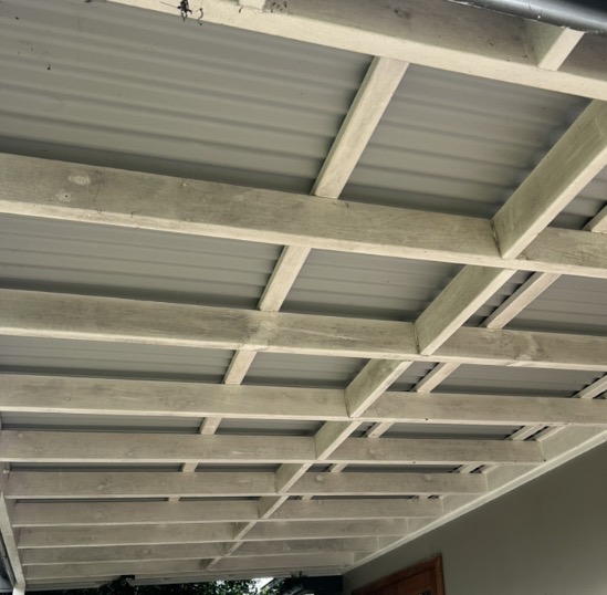 Grimy timber veranda beams and metal ceiling before pressure cleaning